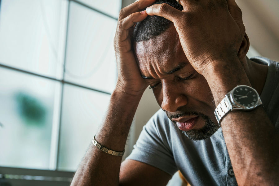 man with anxiety holding his head