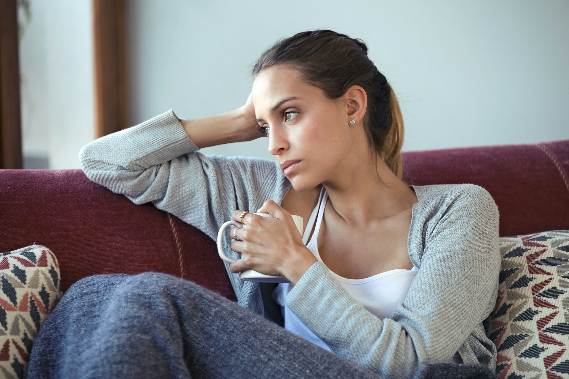 a-woman-sad-holding-a-cup-of-coffee-sitting-on-the-couch