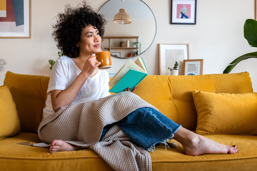 a-woman-drinking-tea-and-reading-on-the-couch