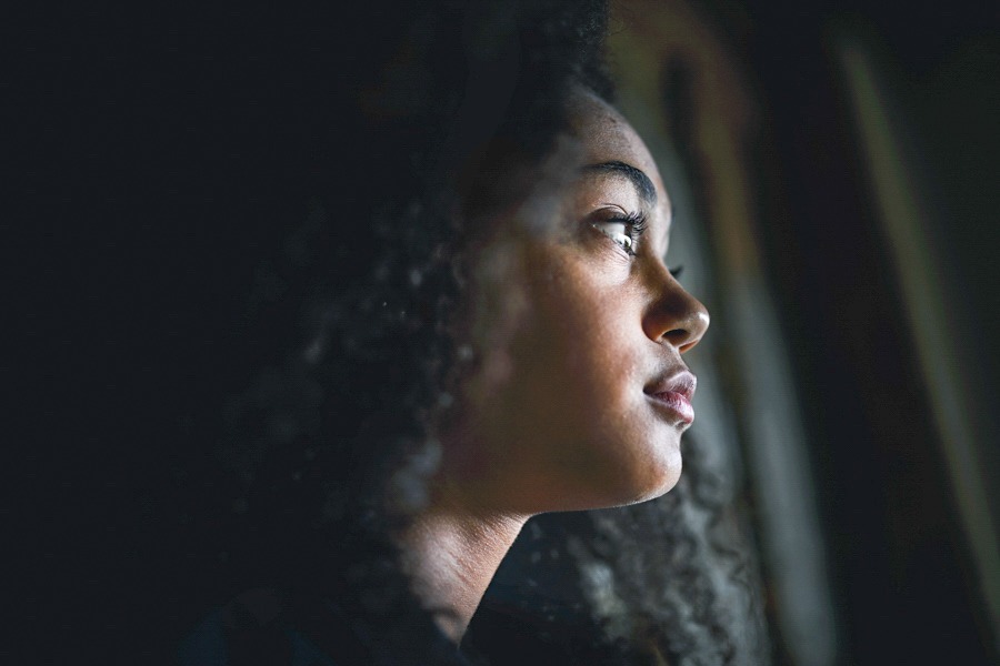 a woman staring out the window depressed