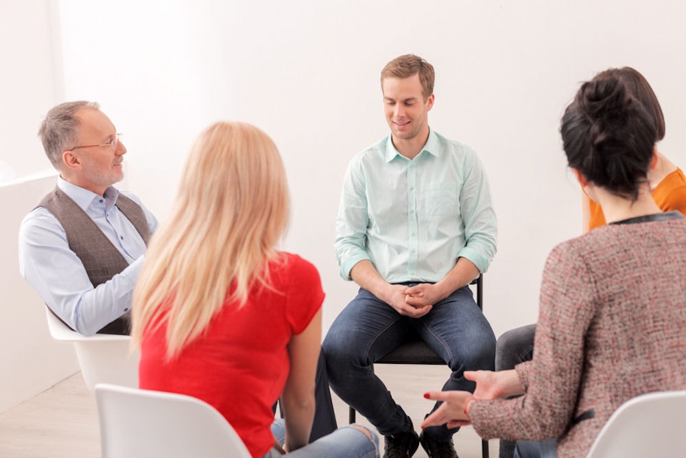 man talking to peers in group therapy session