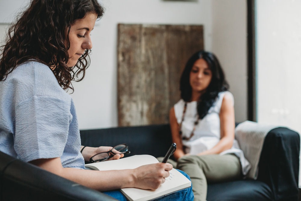 therapist taking notes during an individual therapy session with a patient in a bipolar treatment program