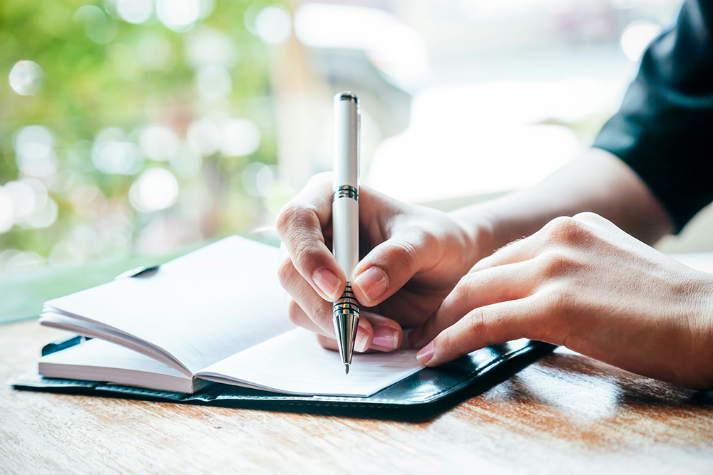 Individual tracking mood swings in a journal as part of bipolar disorder symptom management.