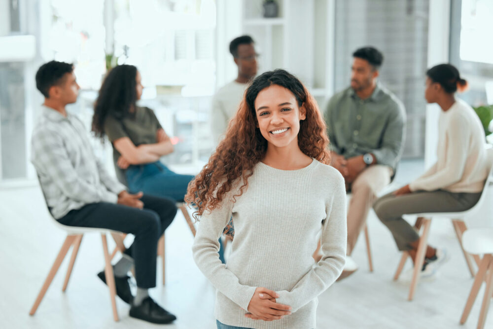 happy woman standing in front of group therapy circle